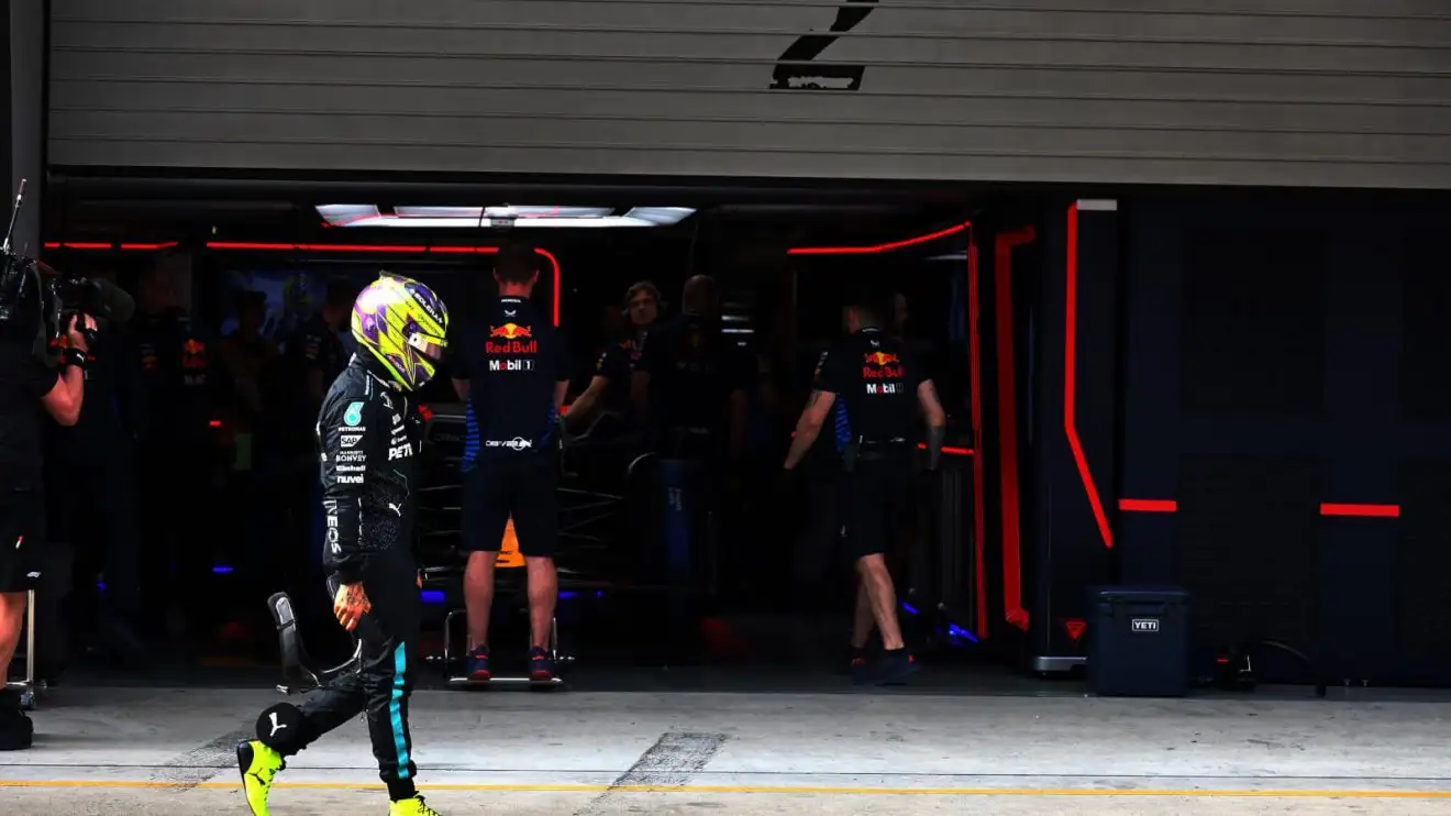 Lewis Hamilton with his head down as he walks past the Red Bull garage