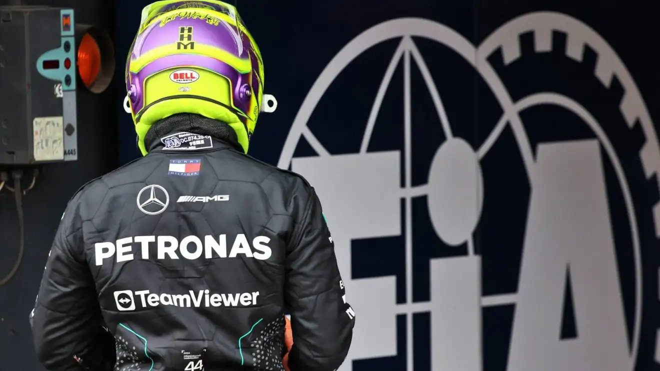 Lewis Hamilton in his Mercedes race gear, alongside the FIA logo, facing away from the camera after dropping out in Q2 at the 2024 Dutch Grand Prix.