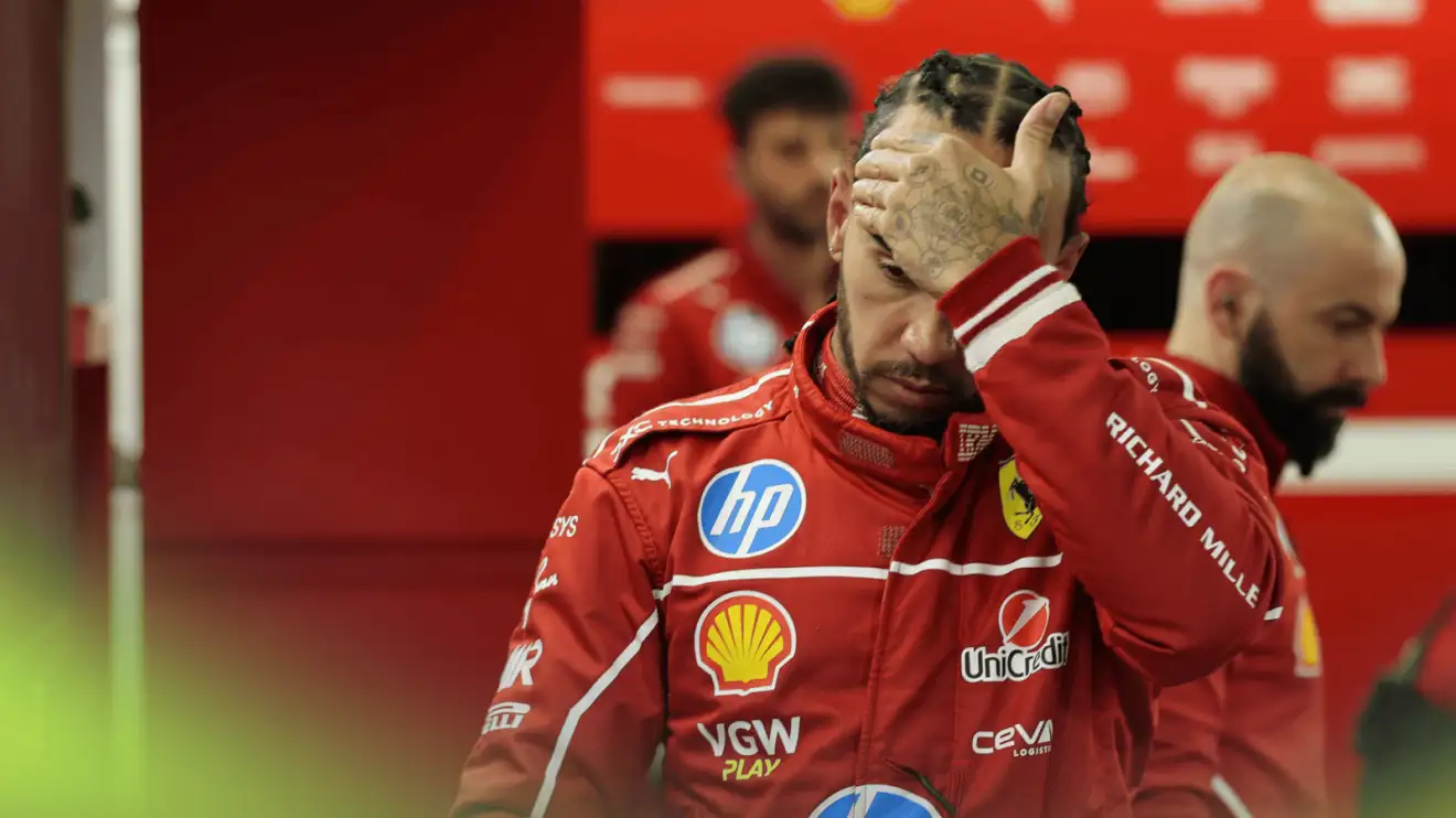 Lewis Hamilton holds his hand to his head as he walks through the Ferrari garage