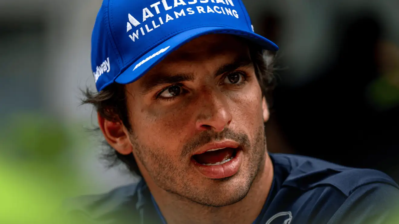 Carlos Sainz looks angry in conversation in the paddock