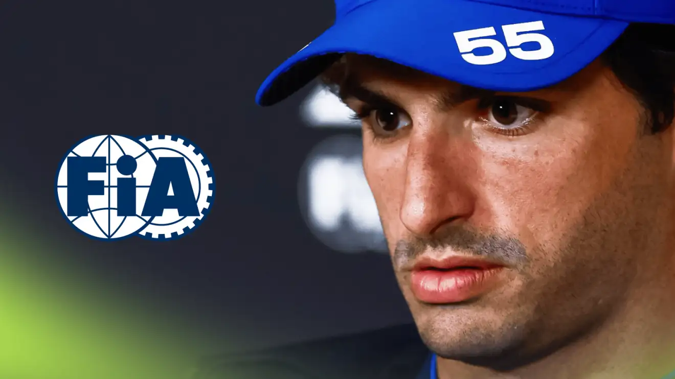 A close-up shot of Carlos Sainz looking downcast in a press conference with a prominent FIA logo alongside him