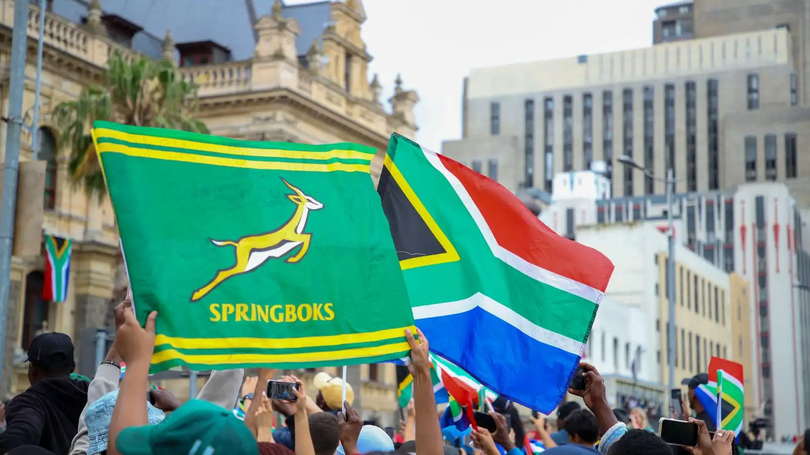 Fans wave a Springbok flag and South African flag in front of the City Hall during the Springbok Trophy tour.