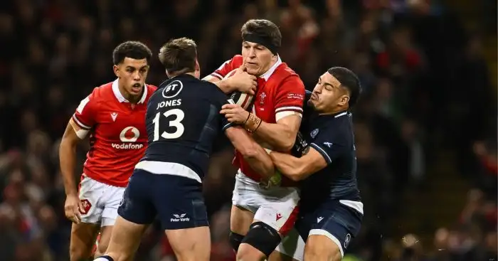 Teddy Williams is tackled by Scotland's Huw Jones and Sione Tuipulotu during the 2024 Guinness Six Nations match Wales vs Scotland at Principality Stadium.