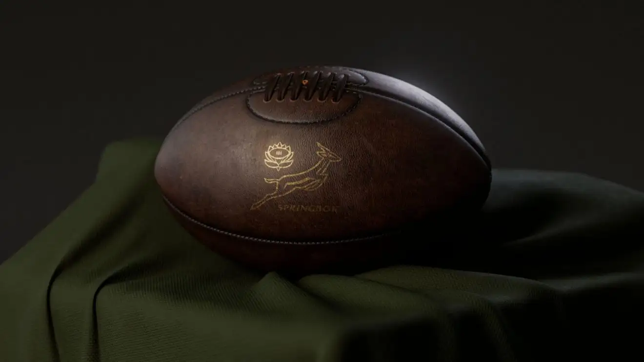 A 3D render of a vintage leather rugby ball with a gold South African rugby logo resting on a draped cloth