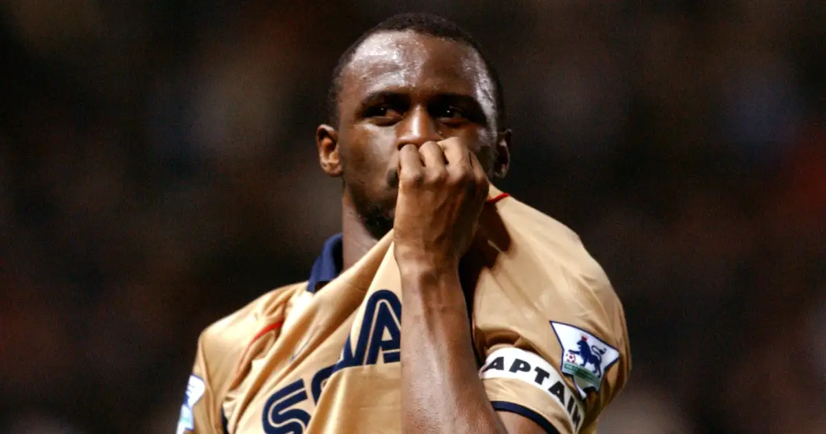 Patrick Vieira celebrates winning the Premiership at Old Trafford by kissing the Arsenal badge.