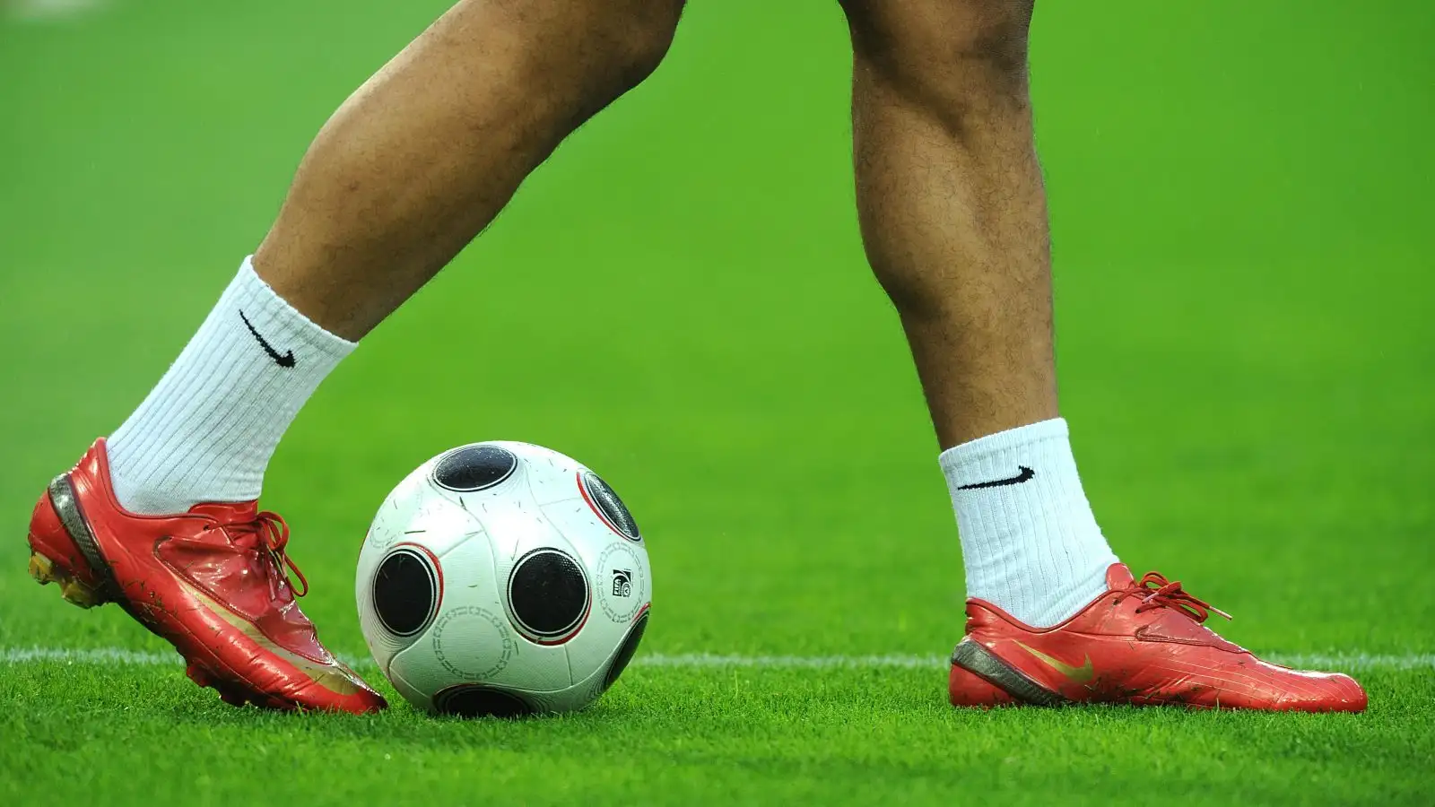 General view of a player wearing red Nike football boots and White Nike socks whilst warming up