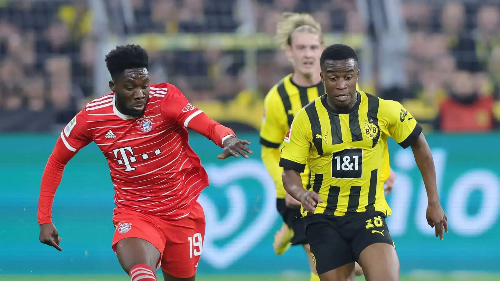 Bayern Munich defender Alphonso Davies tussling with Borussia Dortmund striker Yousouffa Moukoko