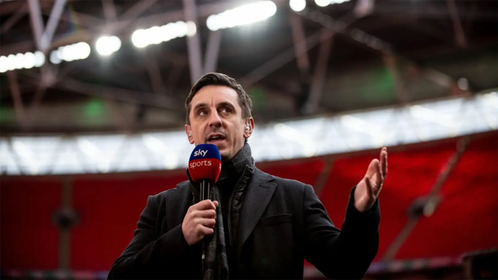 Gary Neville commentating for Sky Sports during a match at Wembley Stadium.