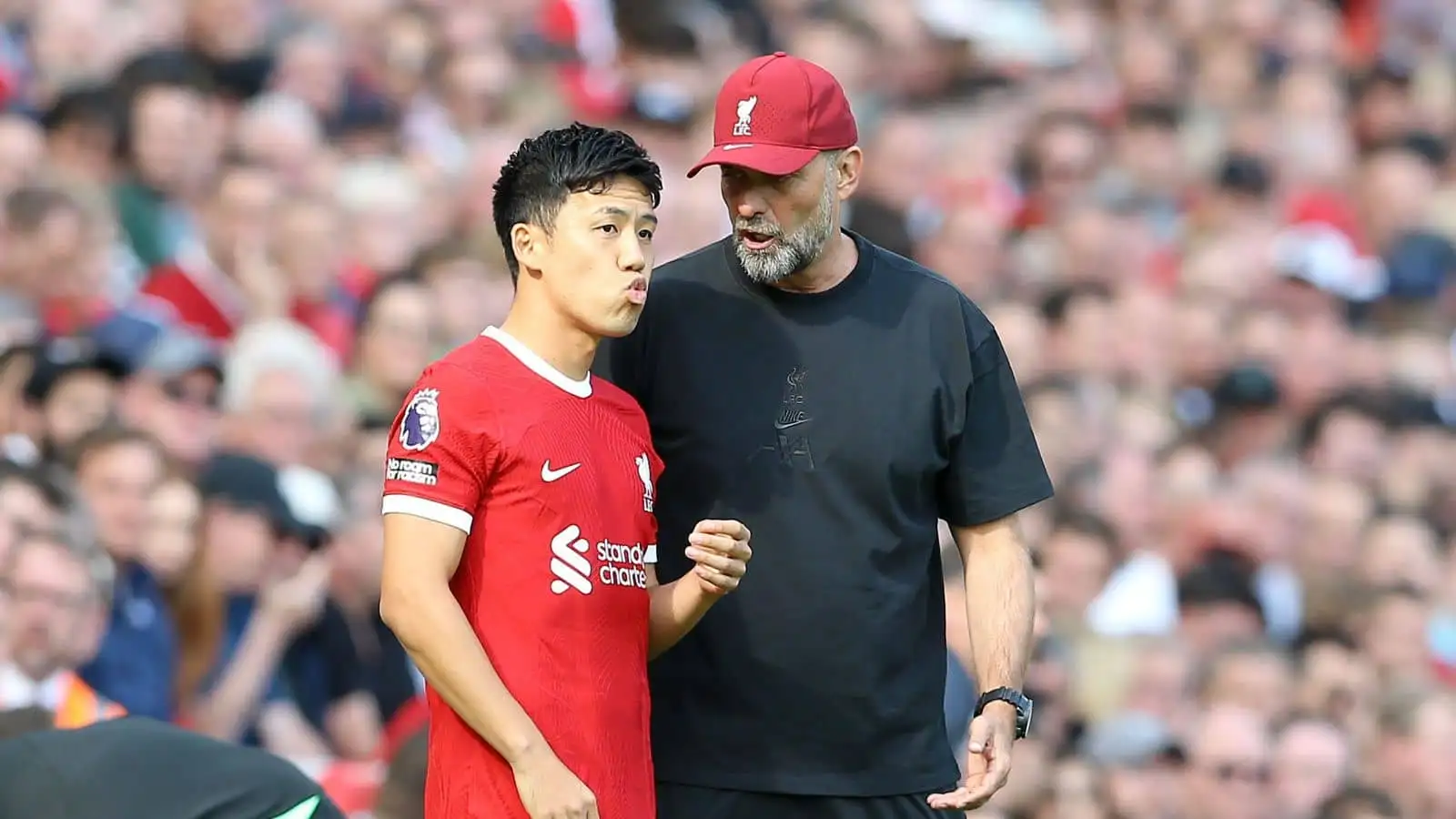 Jurgen Klopp, the manager of Liverpool talks with Wataru Endo of Liverpool prior to him joining the game during the Reds' 3-1 win over Bournemouth at Anfield