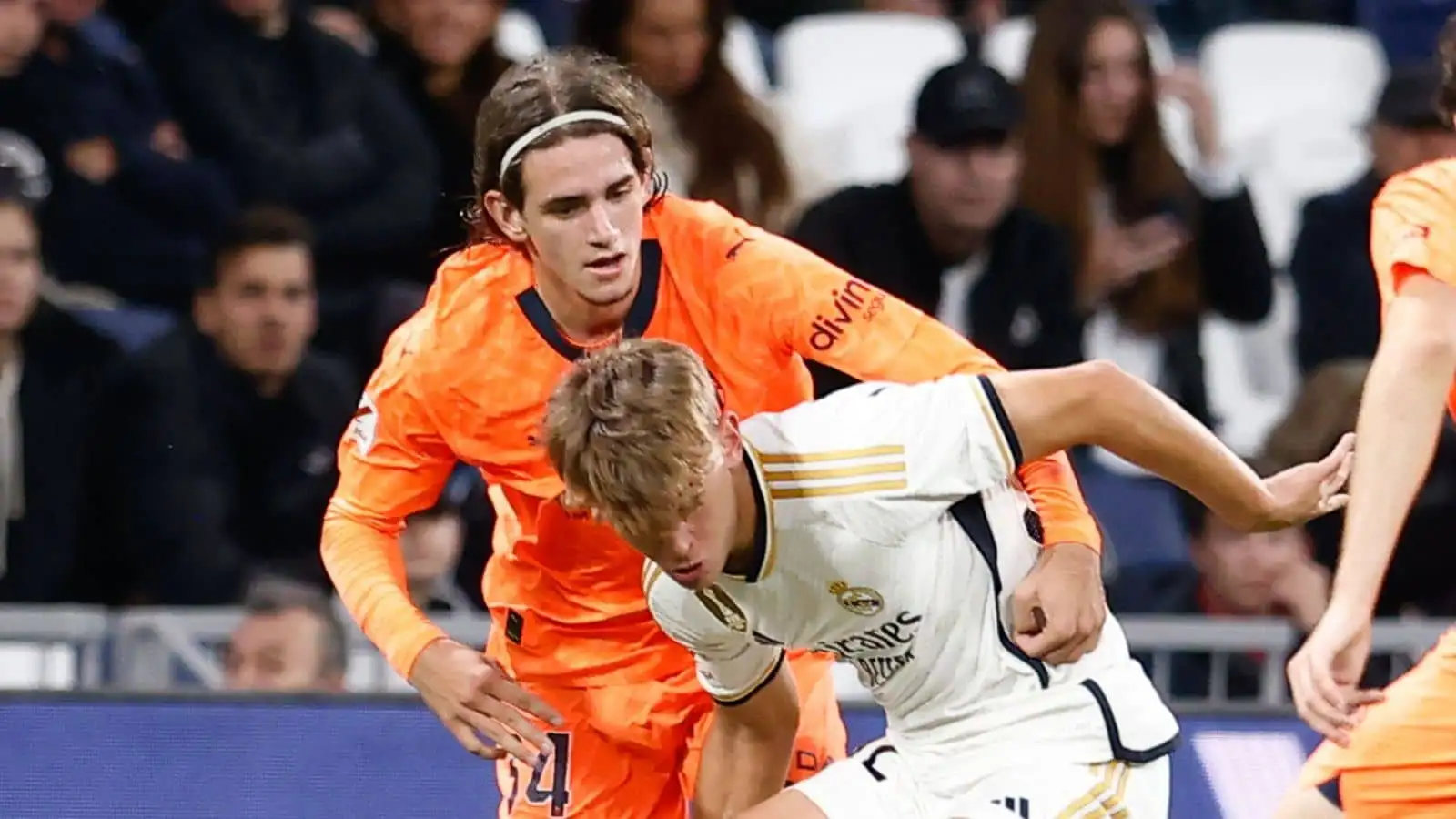 Real Madrid midfielder Nico Paz being challenged by Valencia defender Yarek Gasiorowski