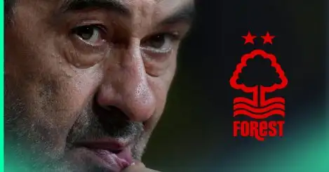 A close-up shot of Maurzizio Sarri in thought with a prominent Nottingham Forest badge alongside him