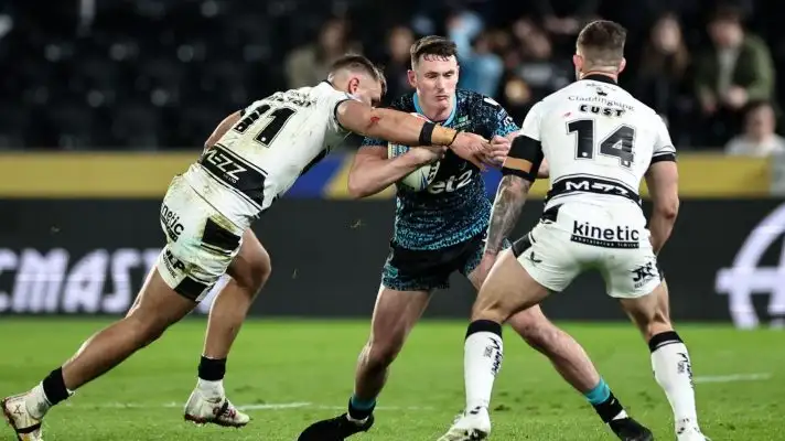 Andy Badrock in action for Leigh Leopards in 2025, being tackled by two Hull FC defenders