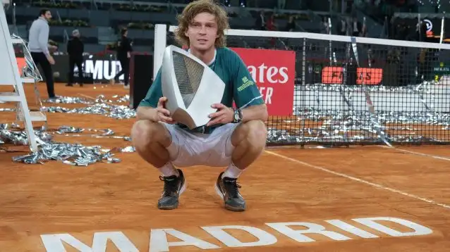 Andrey Rublev kneeling with the Madrid trophy